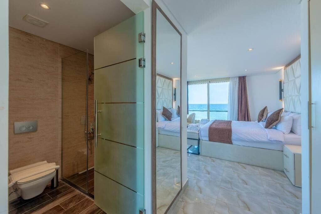 Une chambre d’hôtel moderne dotée d’un grand lit, d’une salle de bain séparée et offrant une vue sur la mer.