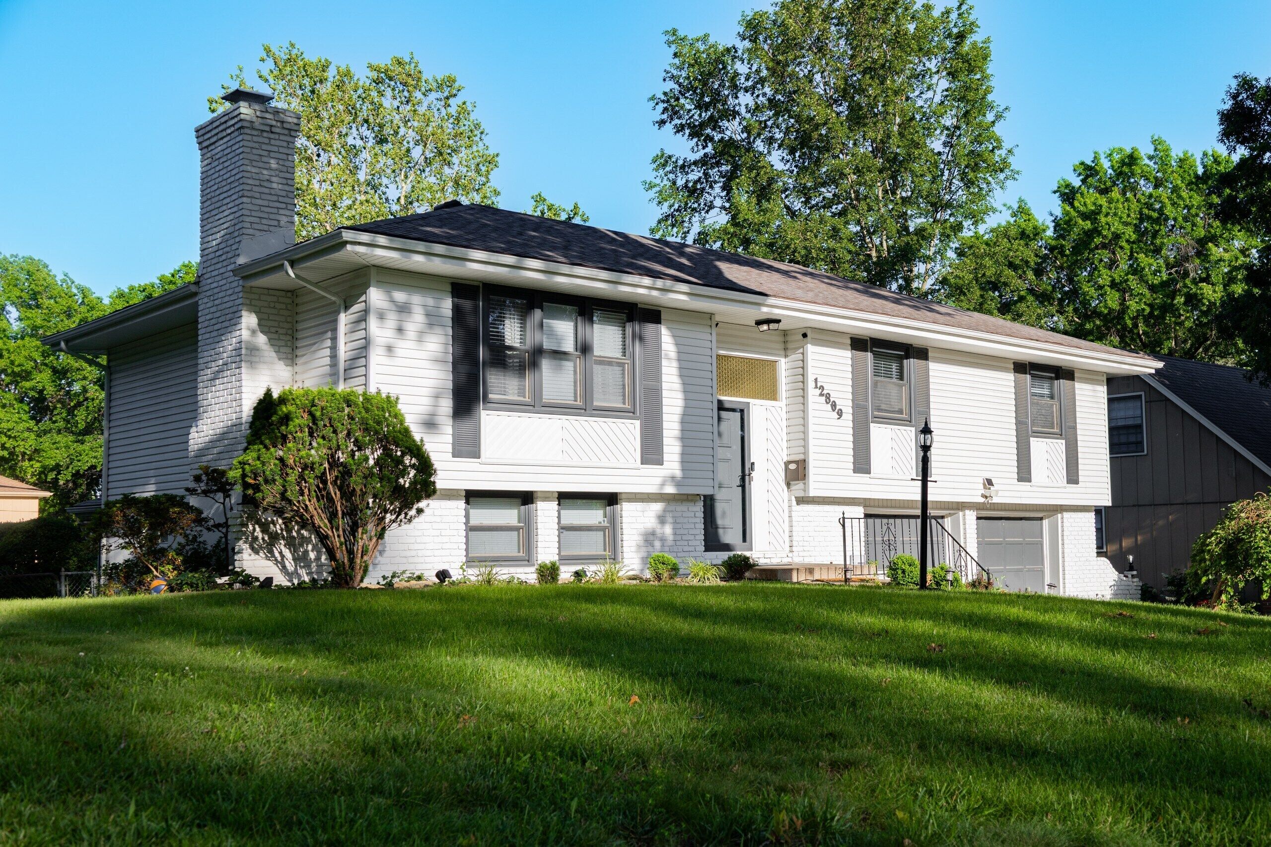 A single-story house with a chimney, a garage, and a well-maintained lawn.