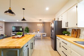 Una cocina moderna con una isla de madera, armarios blancos y un refrigerador empotrado.