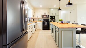 A modern kitchen with a refrigerator, microwave, oven, and a wooden island with seating.