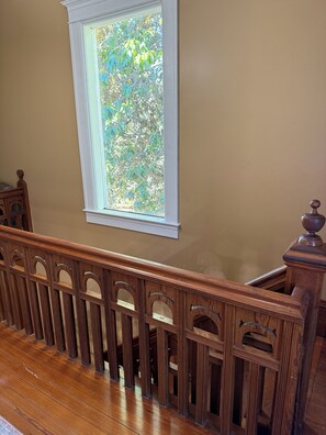 Un escalier en bois avec une balustrade blanche et une fenêtre donnant sur la verdure.