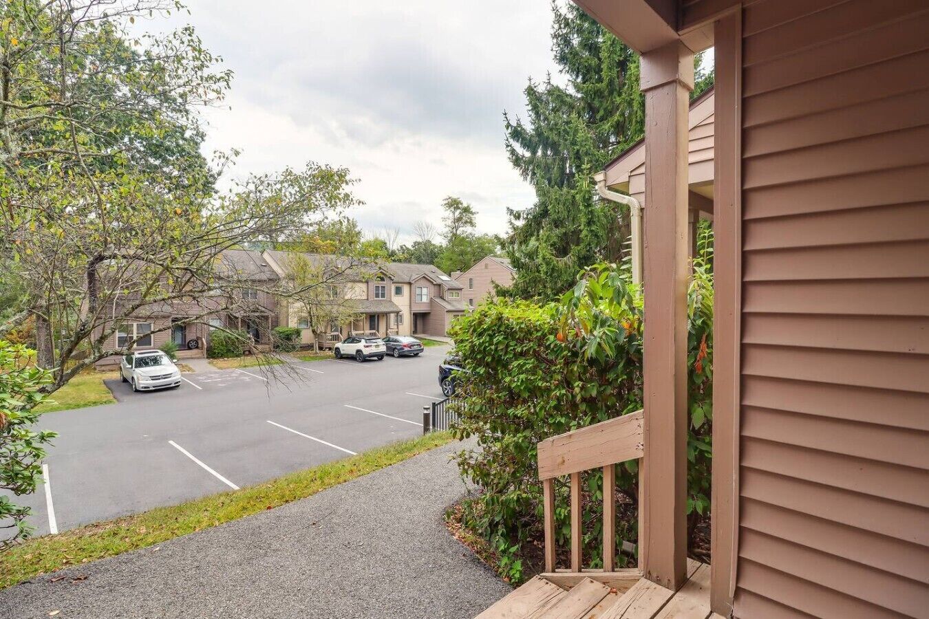 A residential area with a parking lot, houses, and a wooden deck.