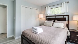 A bedroom with a bed, bedside tables, a window with curtains, and a door. - Pocono Mountains Gem (East Stroudsburg)