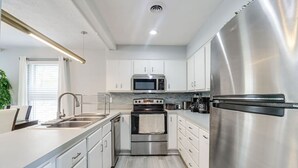 A modern kitchen with stainless steel appliances, white cabinetry, and a light wood floor. - Pocono Mountains Gem (East Stroudsburg)