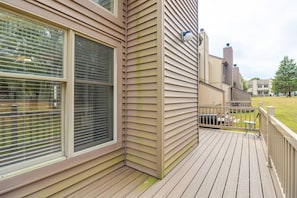 Ein Wohngebäude mit einer Holzdachterrasse, großen Fenstern und einem sichtbaren Außenbereich mit einer Umzäunung.