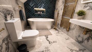 A modern bathroom with a freestanding bathtub, a toilet, a bidet, and a sink.