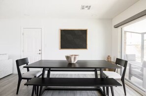 A modern dining area with a dark wooden table, two chairs, a bench, and a decorative bowl. A geometric wall art piece is centered above the table. - Scottsdale Oasis with Heated Pool, Putting Green & Fire Pit (Scottsdale)