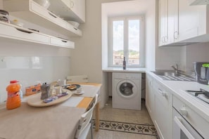 A compact kitchen with a washing machine, a sink, and a window with a view. - Campo de' Fiori | Panoramic View & 2 Bedrooms (Rome)