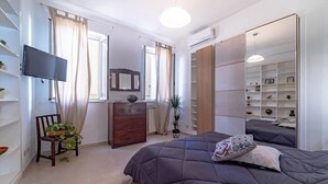 A bedroom with a bed, a dresser, a TV, and a large mirror. - Campo de' Fiori | Private Rooftop Terrace (Rome)