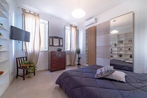 Ein Schlafzimmer mit Bett, Schminktisch, Fernseher und einem großen Spiegel.