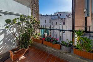 A balcony with terracotta tiles, potted plants, and a view of neighboring buildings. - Campo de' Fiori | Private Rooftop Terrace (Rome)