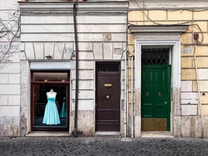 A building facade with numbered doors, a mannequin in a dress, and a green door. - Campo de' Fiori | Private Rooftop Terrace (Rome)