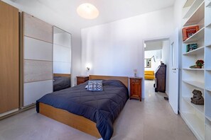 A bedroom with a bed, bedside tables, a wardrobe, and a bookshelf. - Campo de' Fiori | Private Rooftop Terrace (Rome)