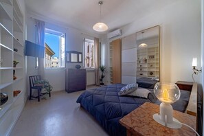 A modern bedroom with a bed, bedside table, and a large window. - Campo de' Fiori | Private Rooftop Terrace (Rome)