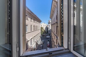 A view from a window overlooking a street with buildings and parked cars. - Campo de' Fiori | Private Rooftop Terrace (Rome)