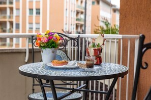 A round table with a decorative glass top, a flower vase with colorful flowers, a muffin on a plate, and a glass of iced coffee with a red straw. - Vatican Shabby double bedrooms (Rome)