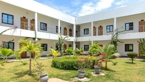 A multi-story building with a courtyard featuring potted plants and a small garden. - Le relais de Kolda  (Kolda)