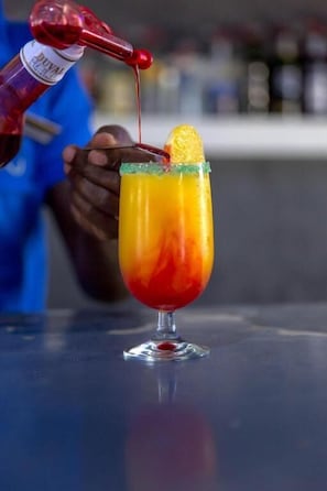 Cóctel siendo servido en un vaso con una guarnición de fruta.