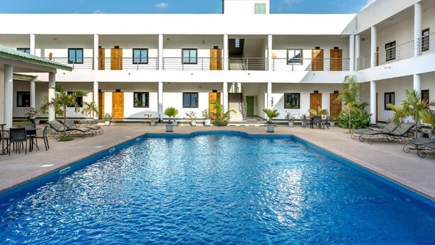 A hotel with a central swimming pool, multiple balconies, and outdoor seating areas. - Le relais de Kolda  (Kolda)