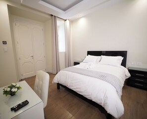 Una habitación de hotel con cama, escritorio, silla y control remoto.