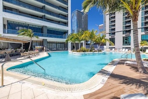 A swimming pool with lounge chairs and palm trees, surrounded by modern buildings. - Beautiful 2 Bed 2 Bath with balcony in Downtown (Miami)