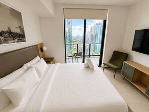 A hotel room with a large bed, a TV mounted on the wall, a balcony with a view of the city, and a chair. - Beautiful 2 Bed 2 Bath with balcony in Downtown (Miami)