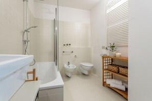 A modern bathroom with a bathtub, shower, toilet, and a shelf with towels. - Lakefront Villa Giulia, PK, Hot Tub, Gym! (Carate Urio)