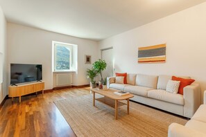A modern living room with a flat-screen TV, a sofa, a coffee table, and a large window. - Lakefront Villa Giulia, PK, Hot Tub, Gym! (Carate Urio)