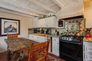 A kitchen with white cabinets, a wooden table, and a tiled backsplash. - Elegant Upscale Adobe Casita in Los Ranchos de Albuquerque District (Los Ranchos de Albuquerque)