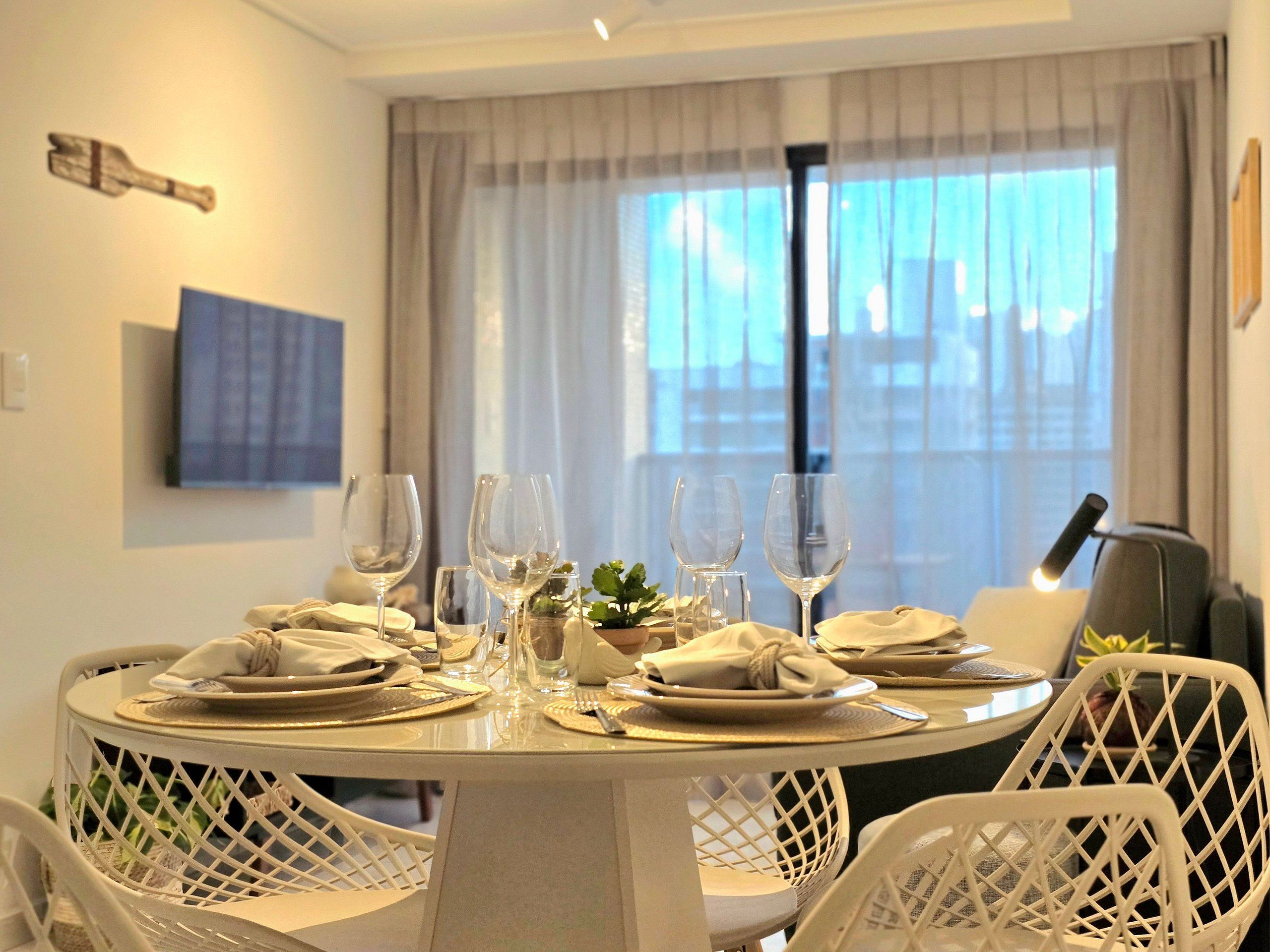 A dining area with a round table set for four, surrounded by white chairs with a lattice design.