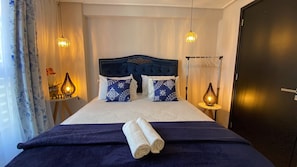 A hotel room with a bed, two bedside lamps, a dark blue headboard, and a dark blue bedspread. - Move By Hosppedar (João Pessoa)