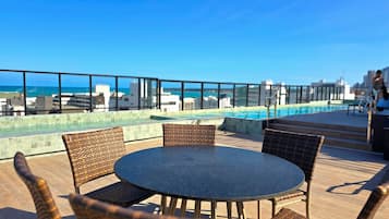 Zona de piscina en la azotea con vistas al océano y al paisaje urbano.
