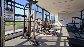 Una palestra con diverse attrezzature per esercizi, ampie finestre e vista sull'esterno.