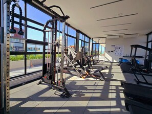 Una palestra con diverse attrezzature per esercizi, ampie finestre e vista sull'esterno.