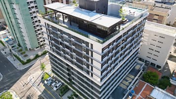 Un edificio de varios pisos con terraza en la azotea y zona de estacionamiento.