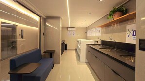 Una habitación de hotel moderna con zona de estar, lavadora y lavamanos.