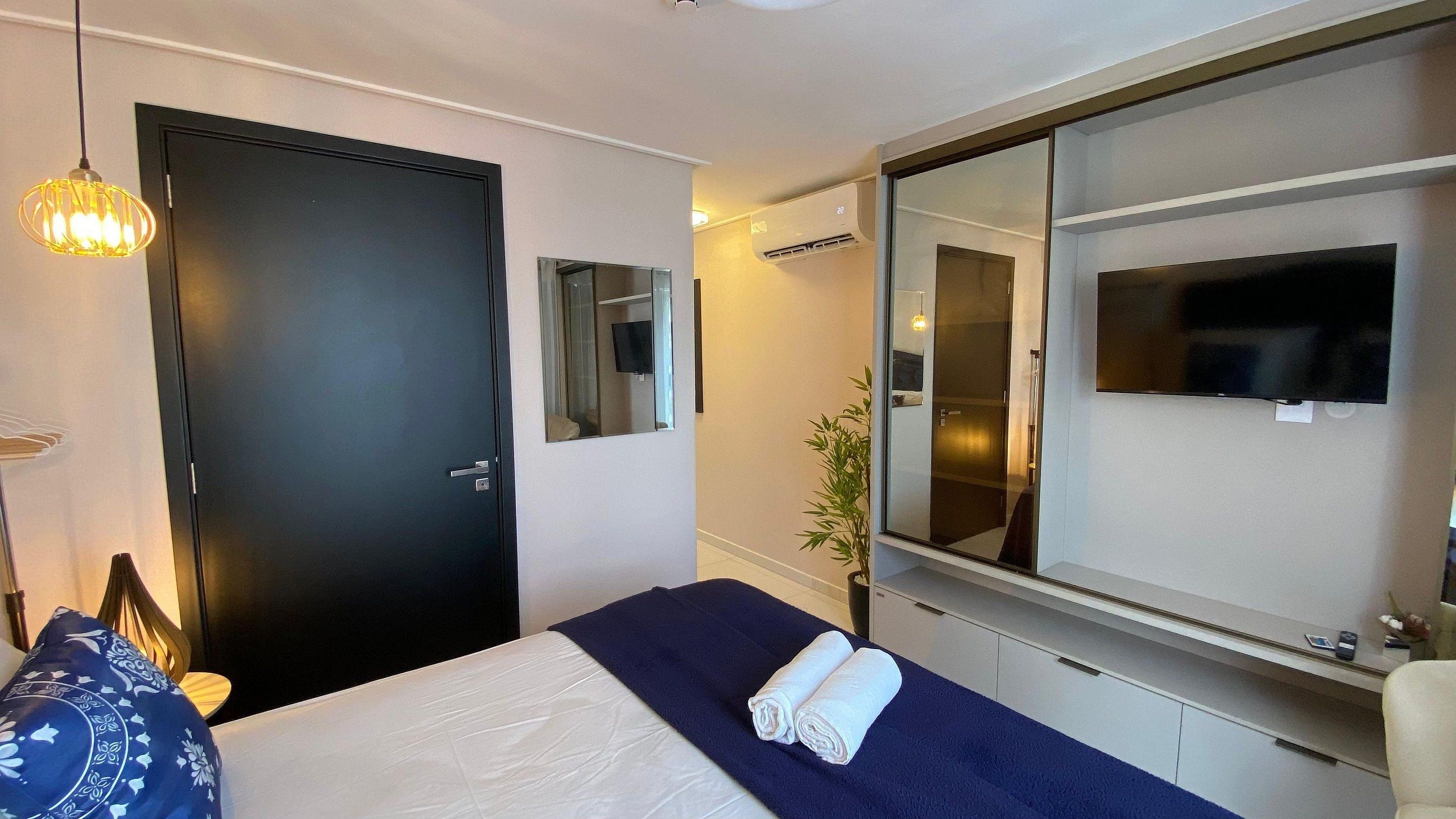 Une chambre d’hôtel avec un lit, un grand miroir, une télévision et une porte.