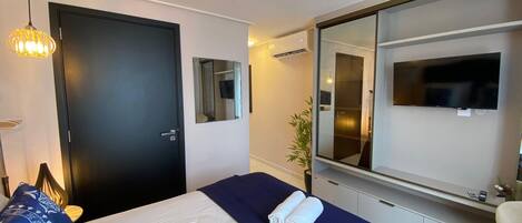 Une chambre d’hôtel avec un lit, un grand miroir, une télévision et une porte.