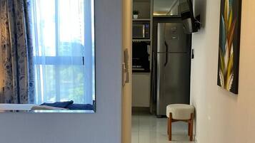 A hallway with a kitchen area, a refrigerator, and a dining chair.