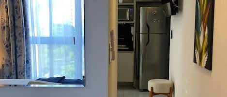 A hallway with a kitchen area, a refrigerator, and a dining chair.
