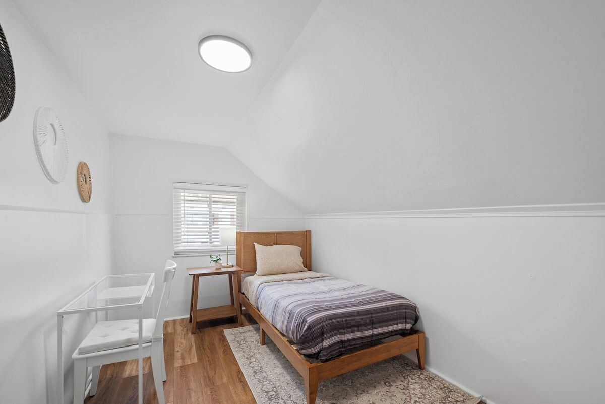 A bedroom with a single bed, a desk, and a chair.