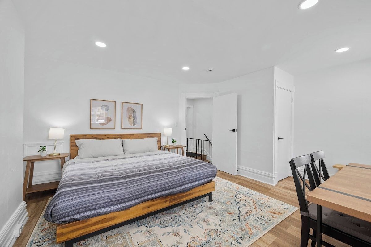 A bedroom with a bed, bedside tables, a nightstand, a desk, and a chair.