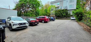 A parking lot with several cars, a building with a metal exterior, and trees in the background.
