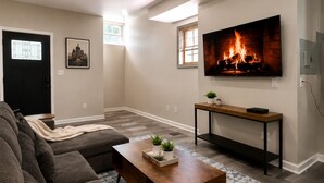 Un salon avec un canapé, une table basse, un téléviseur et une cheminée.