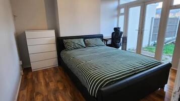 A bedroom with a large bed, a dresser, and a window.