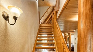 Una escalera de madera con barandilla y luminarias fijadas a la pared.