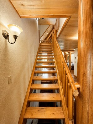 Eine Holztreppe mit Geländer und Wandleuchten.