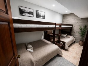 A bunk bed room with a wooden headboard, a small bedside table, and a wall-mounted shelf. - Ursa Minor Lodge (Deer)