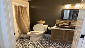 A bathroom with a toilet, a sink with a decorative backsplash, patterned floor tiles, and a shower curtain. - Two bedroom cozy apartment in central location, 15 minute from historic downtown (St. John's)