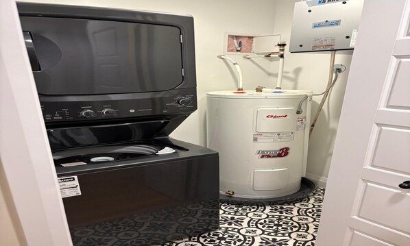 A compact laundry room with a washer, dryer, and water heater.